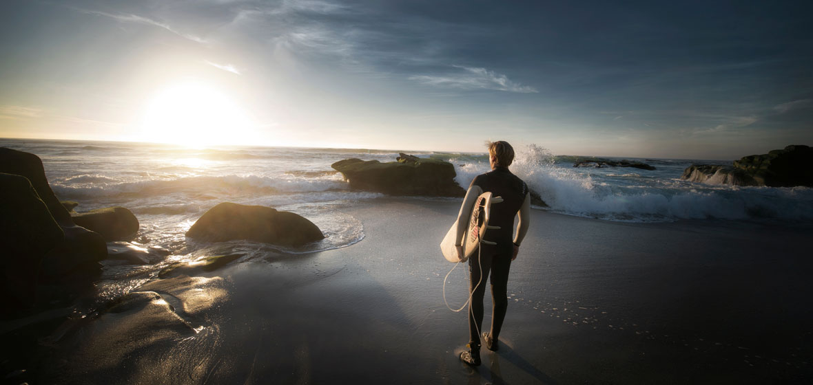 Man with surfboard looks at the ocean