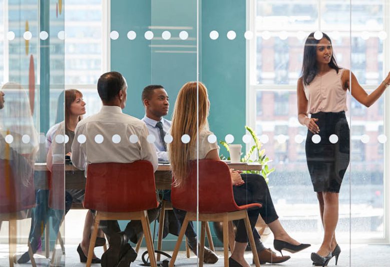 woman gives presentation to group in a boardroom