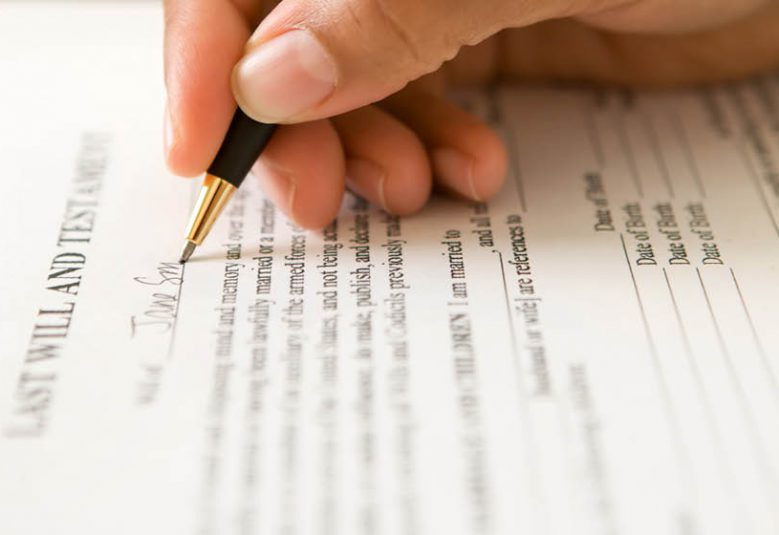 Image of hand signing a will