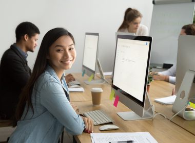 Young employee, sitting at her computer smiling
