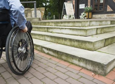 Wheelchair user in front of staircase barrier