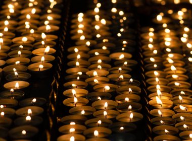Many beautiful lit candles in a row glowing with a golden yellow light