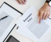 A man reviews insurance policy documents on a desk