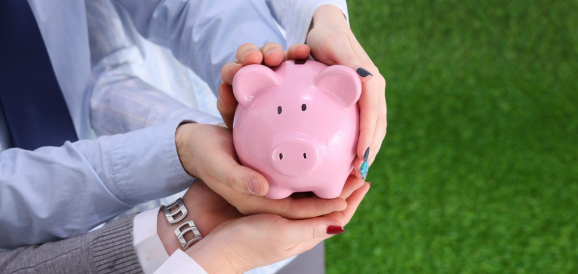 Two people holding a piggy bank