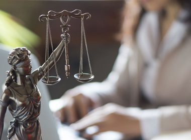 Lady Justice statue next to a woman's laptop