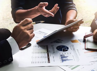 Three people review documents at a desk