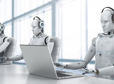 Three robots use laptops
