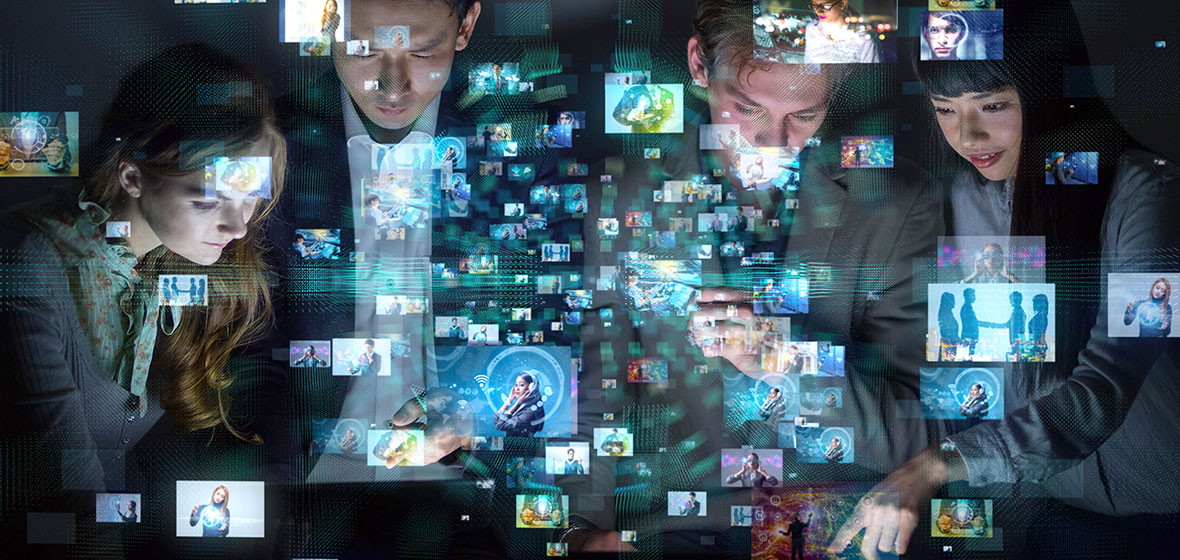 Four people pointing at digital screens