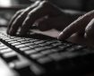 Fingers typing on a keyboard in a dark room