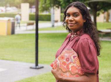 image showing young Aboriginal woman holding folder standing outdoors, to illustrate First Nations Cadetship Program